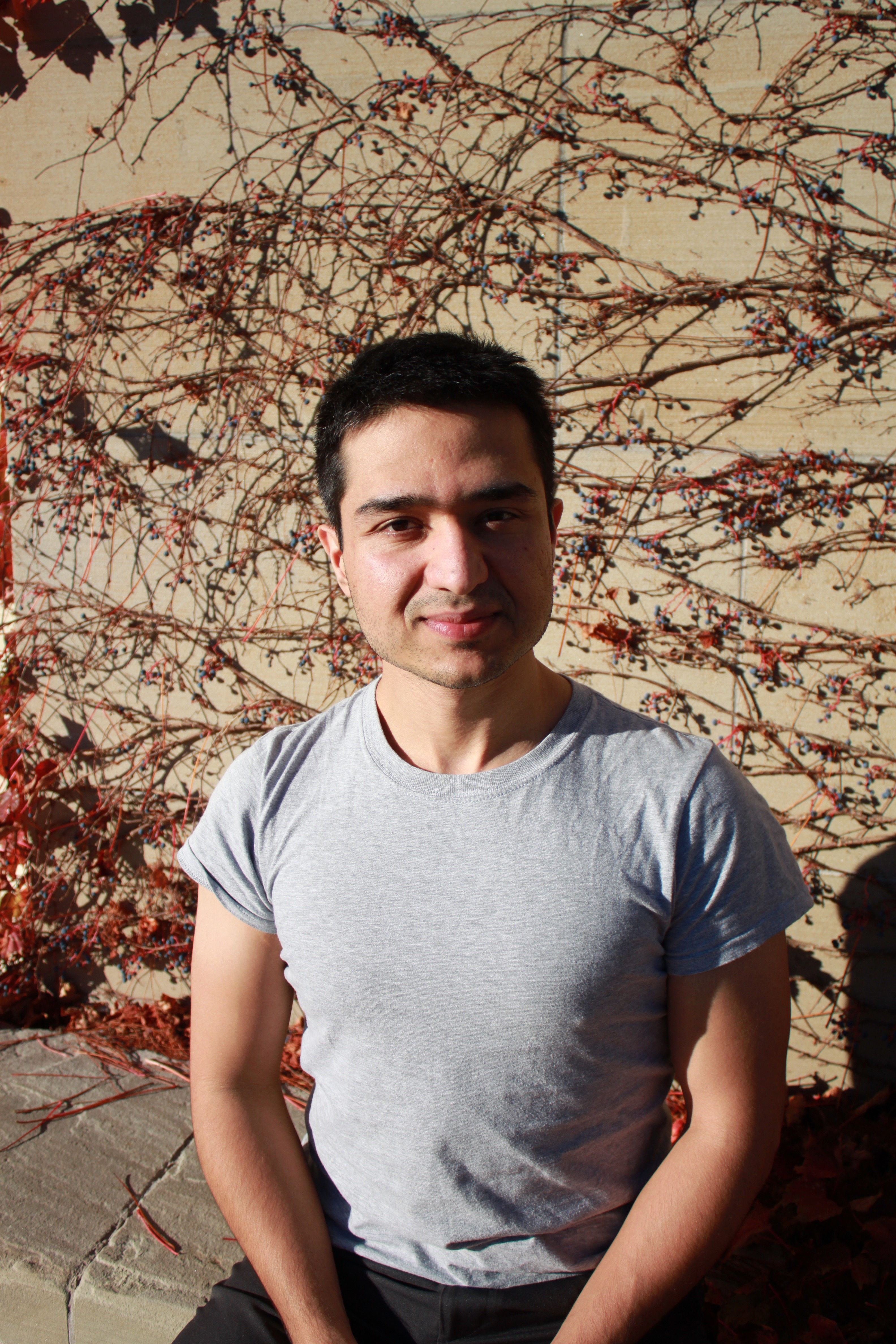 Farhad in a grey shirt, smiling, outdoors