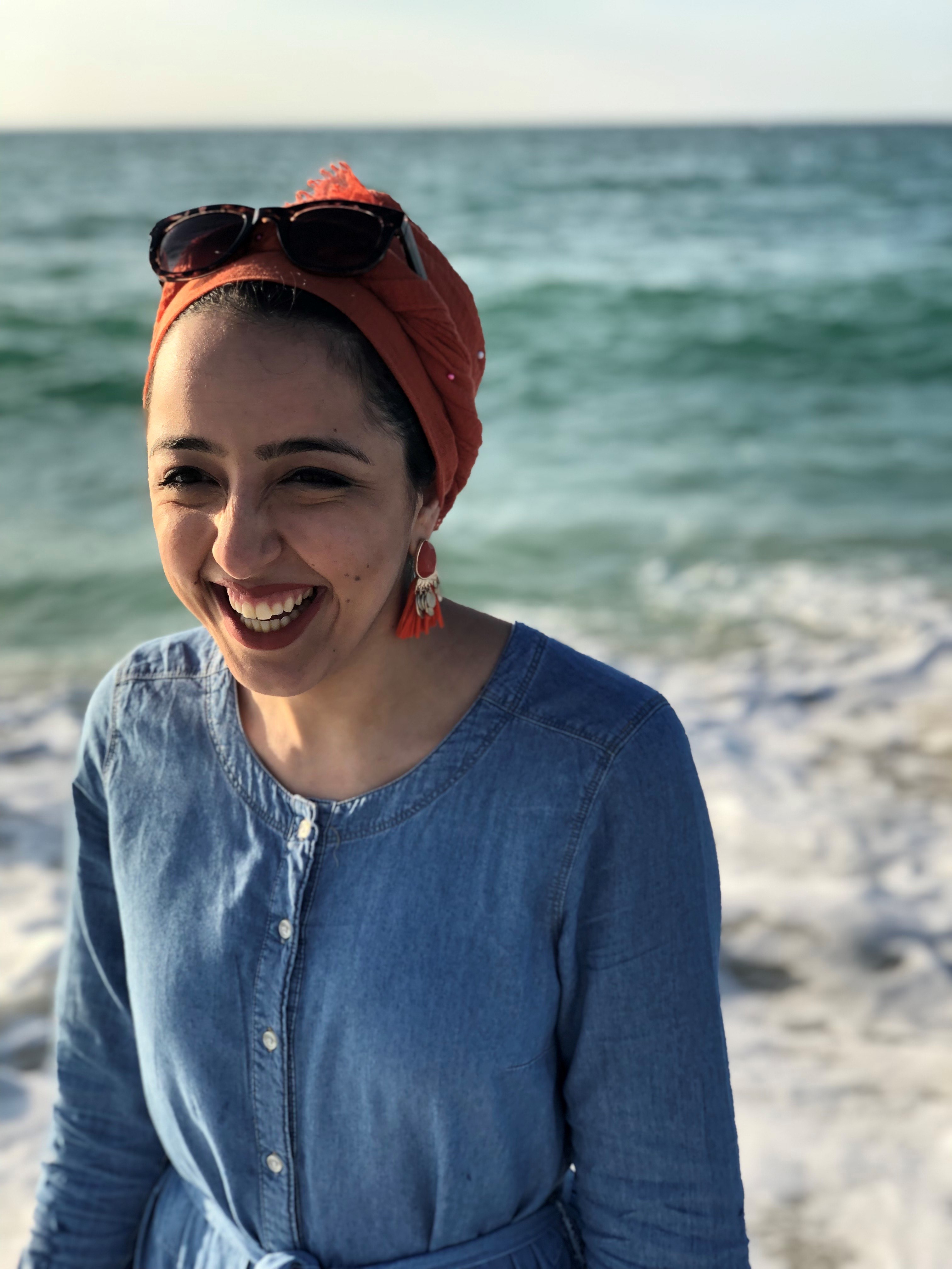 Zinab wearing a blue shirt at the beach with the ocean in the background