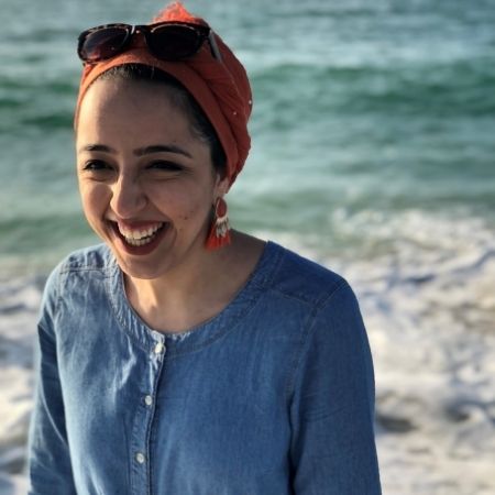 Zinab wearing a blue shirt at the beach with the ocean in the background