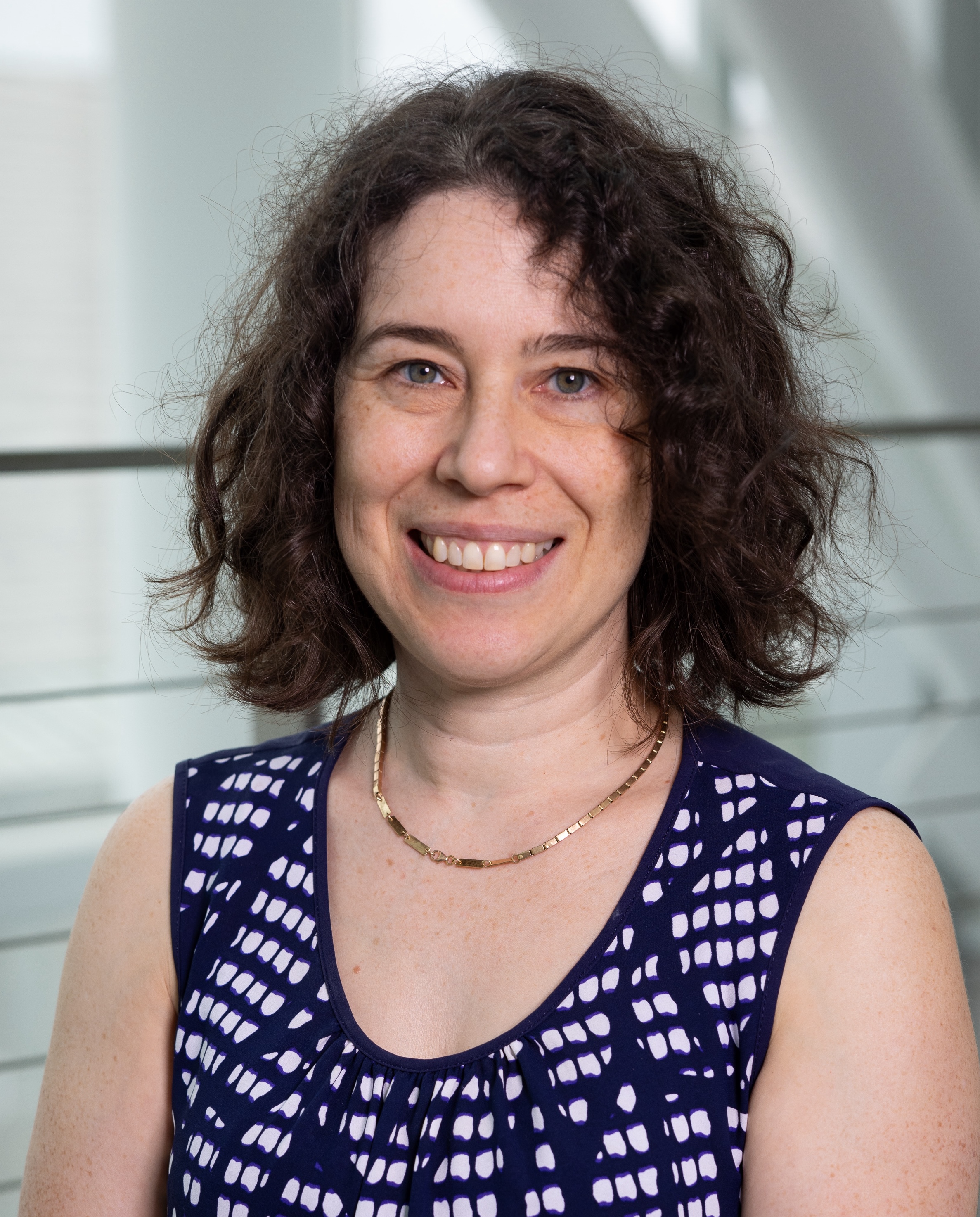 woman, short curly hair, blue top, smiling