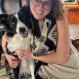 Amanda wearing glasses, in black and white, along with her dog, a border collie