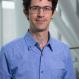 White man, glasses, curly hair, blue shirt